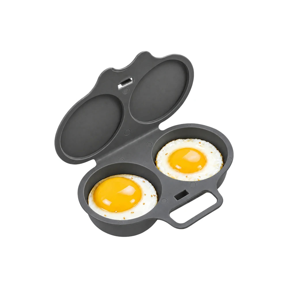 A dark gray silicone egg mold with two oval cavities, shown open with two cooked sunny eggs inside on a plain white background.